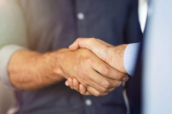 Close-up of two individuals shaking hands, symbolizing agreement and partnership.