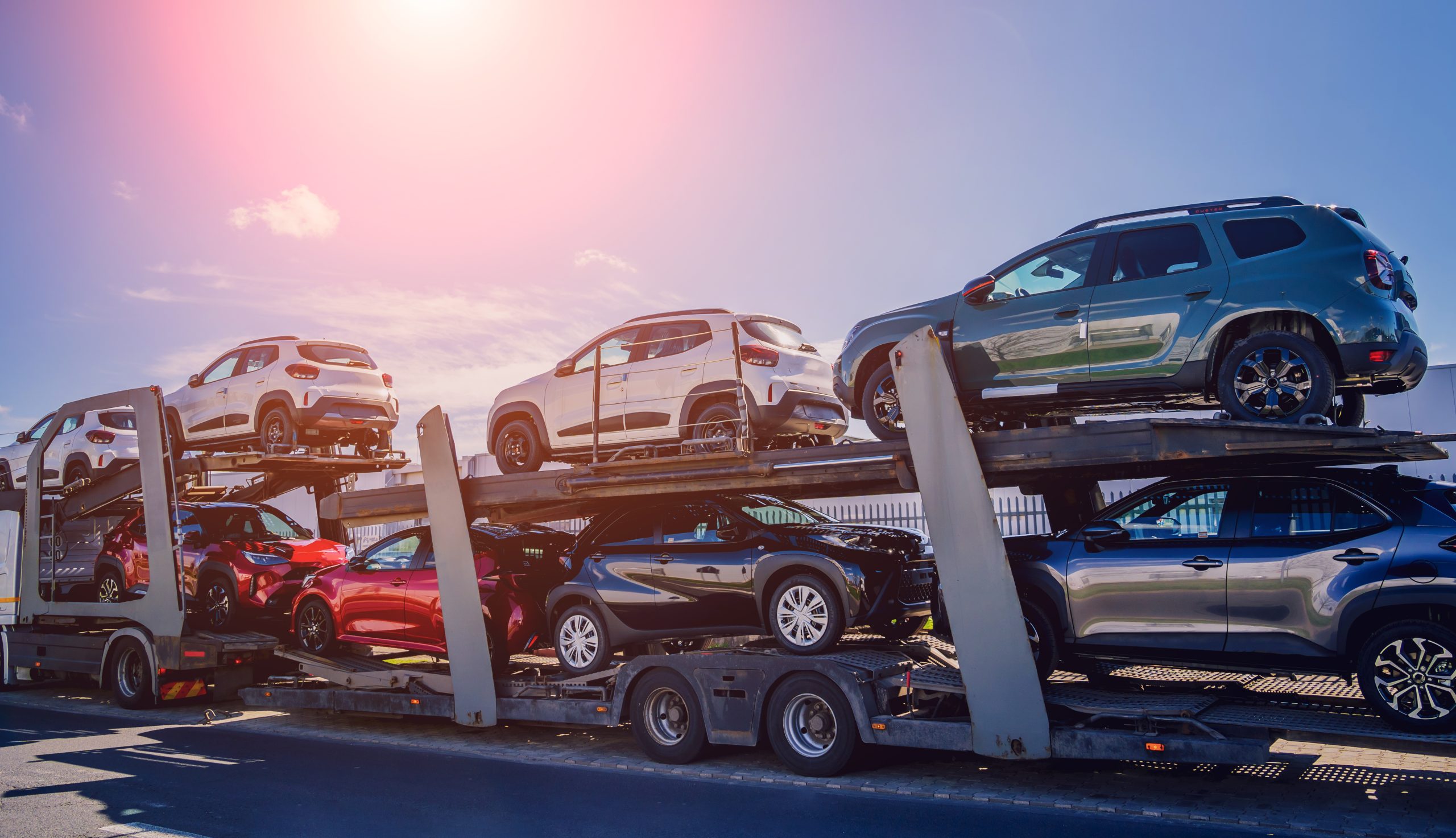 Freight truck transporting multiple cars along a highway.