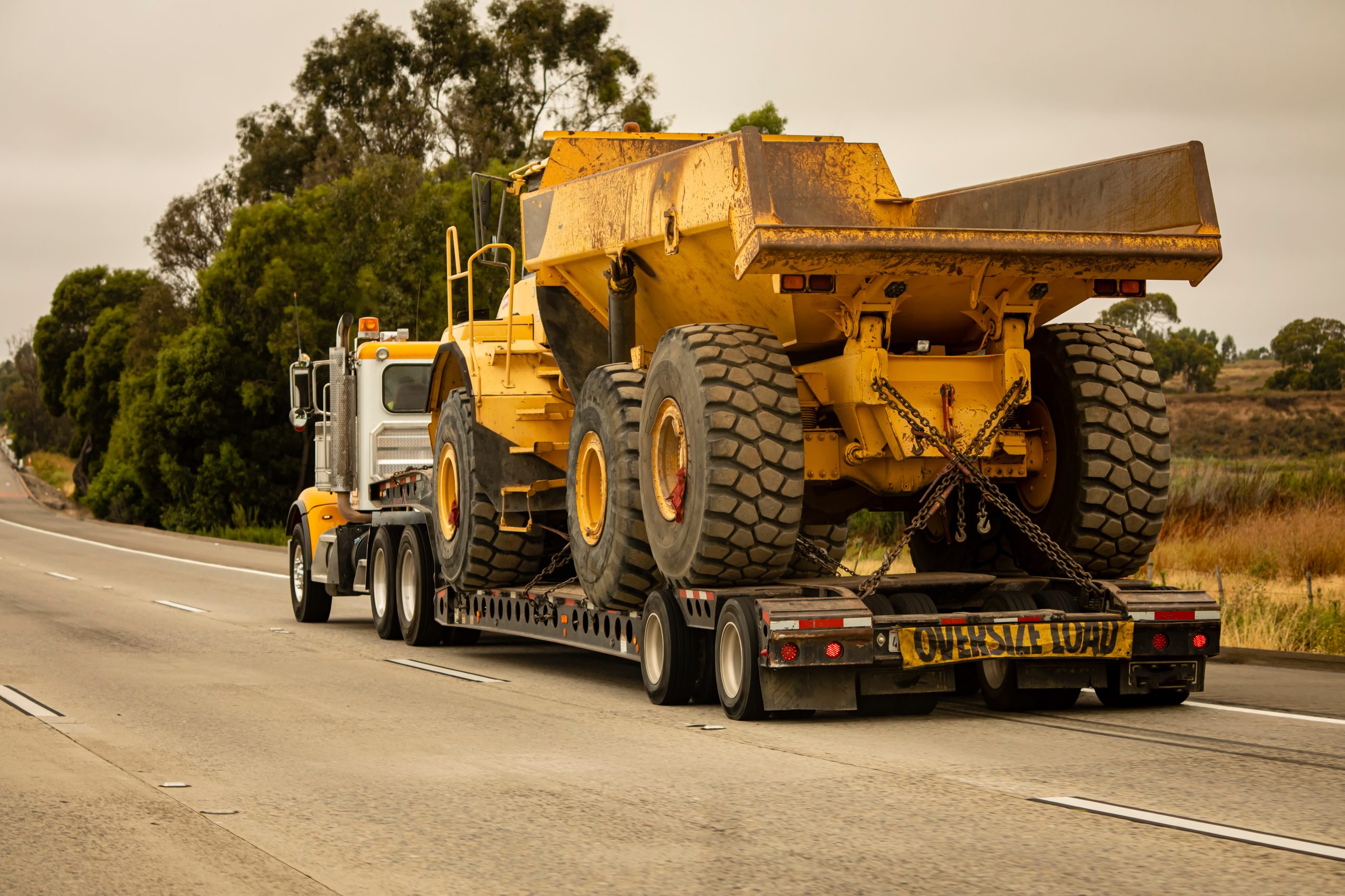 Heavy-duty truck transporting construction vehicles on a flatbed.