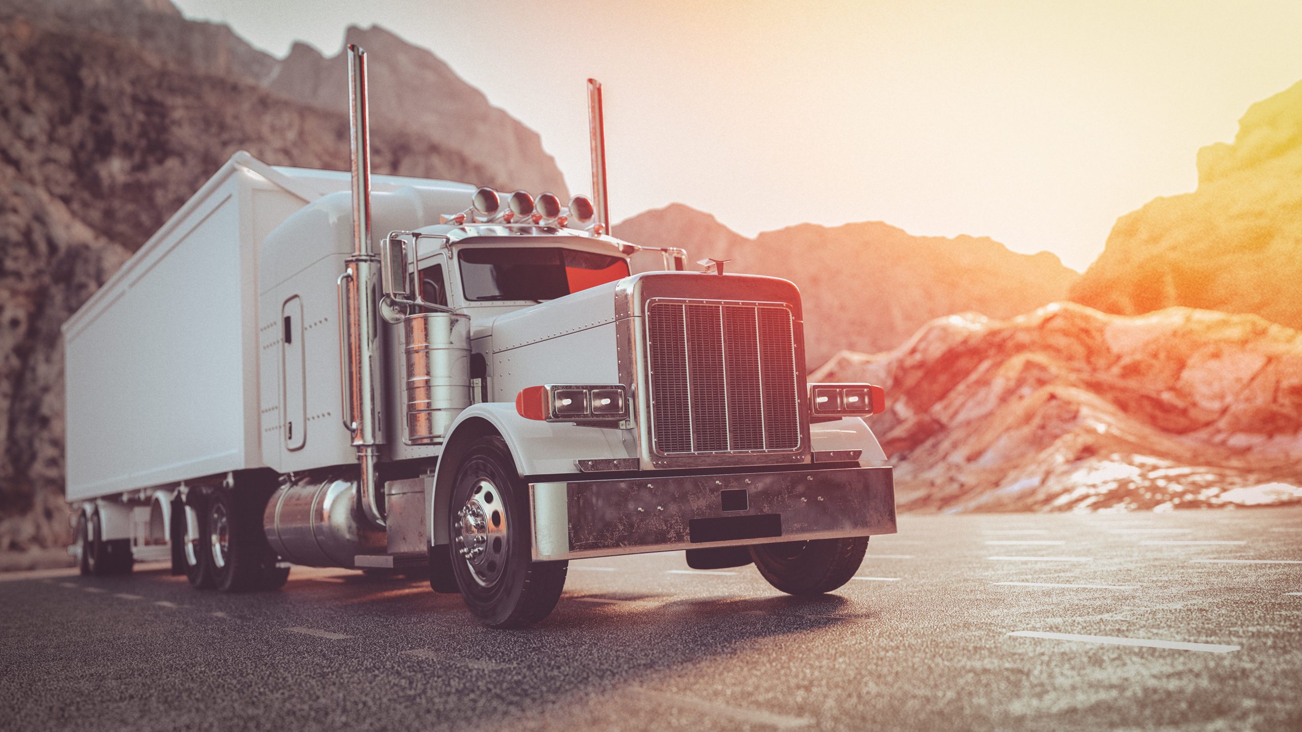 Freight truck traveling on a highway with snow-capped mountains.