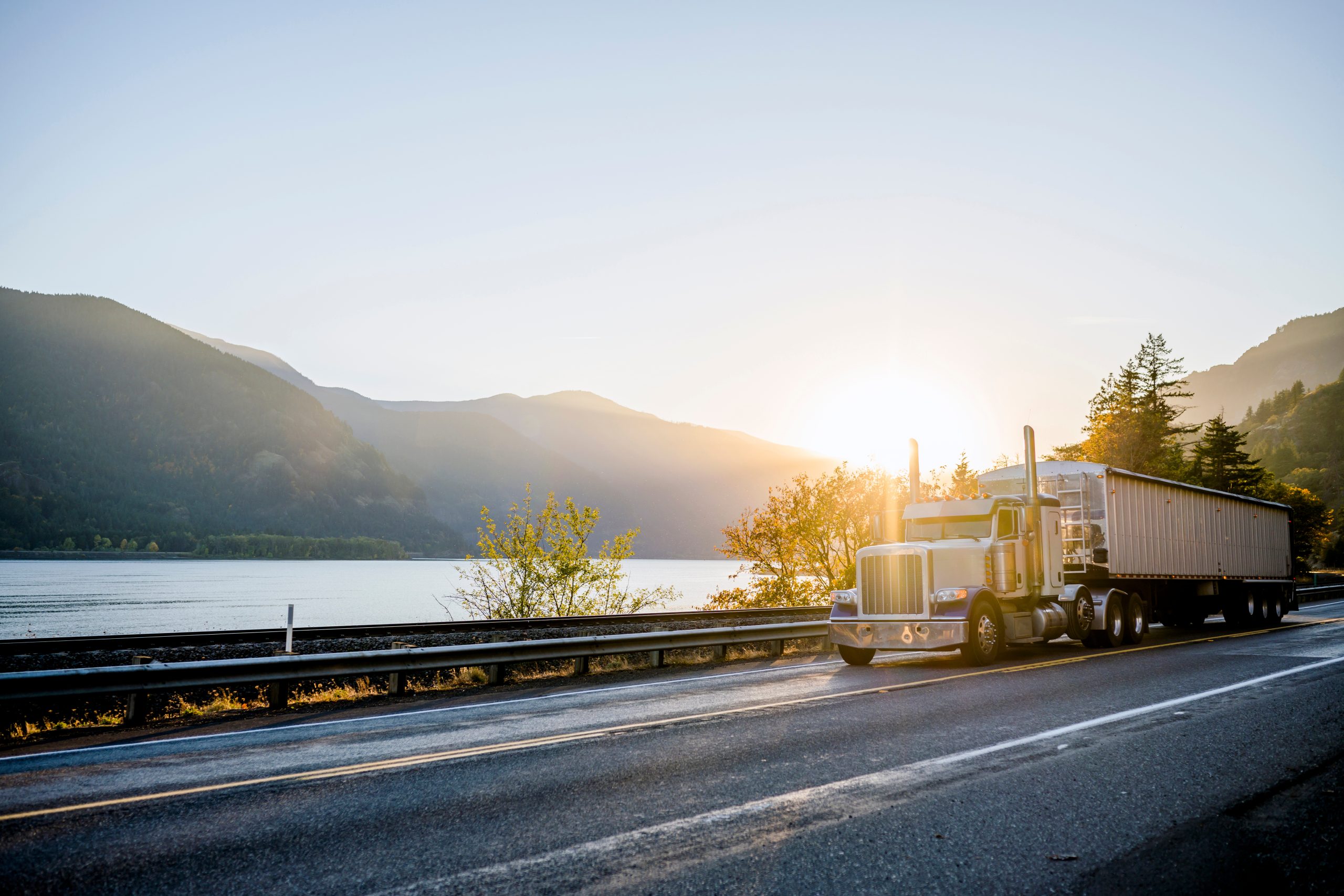 Truck carrying large equipment through a mountainous region.